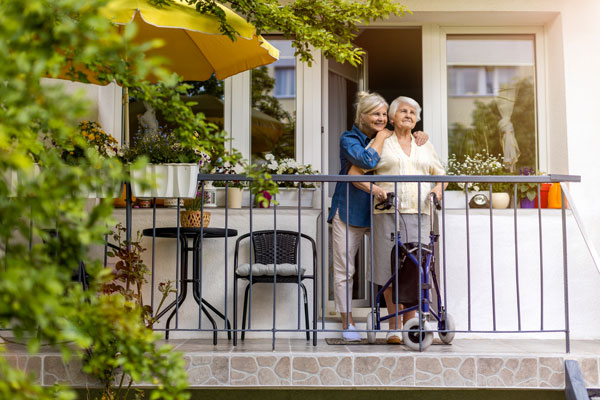 Elderly woman and caregiver on balcony