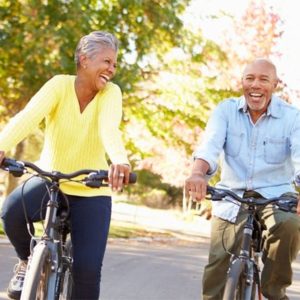 Older adult couple riding bikes together on path in park in the spring