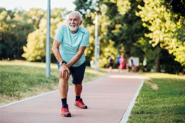 Older adult man stretching before his jog in the park