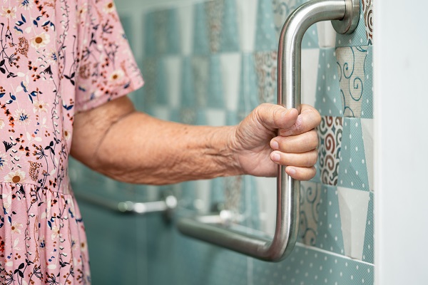 Arm of older adult woman holding the safety bar in a standing shower